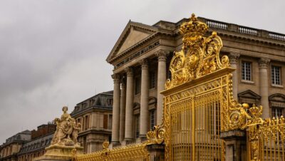 Reja real dorada del Palacio de Versalles. Es de estilo barroco. Al fondo, el edificio principal.